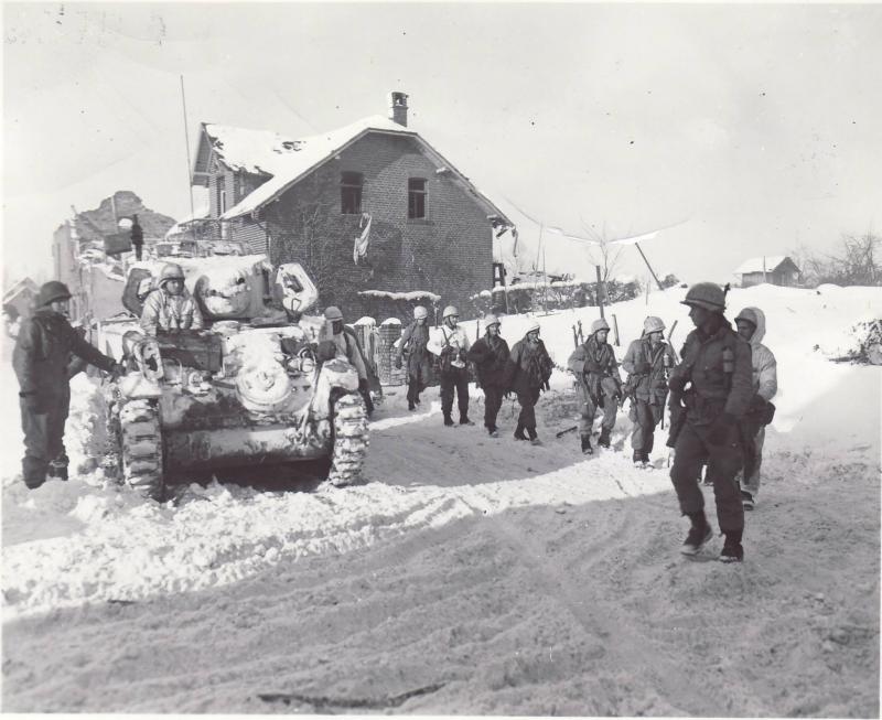 Parachute Infantrymen pass an M5A1 light tank of 7 Armored Division